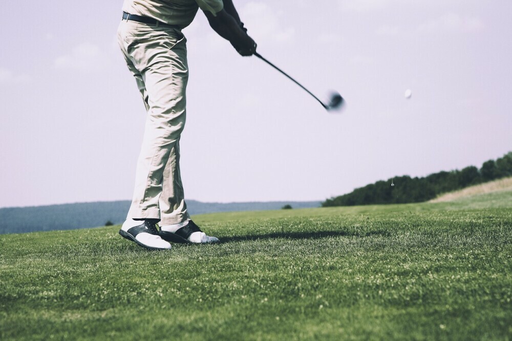 Golfer completing his follow through in his swing after making contact with the ball